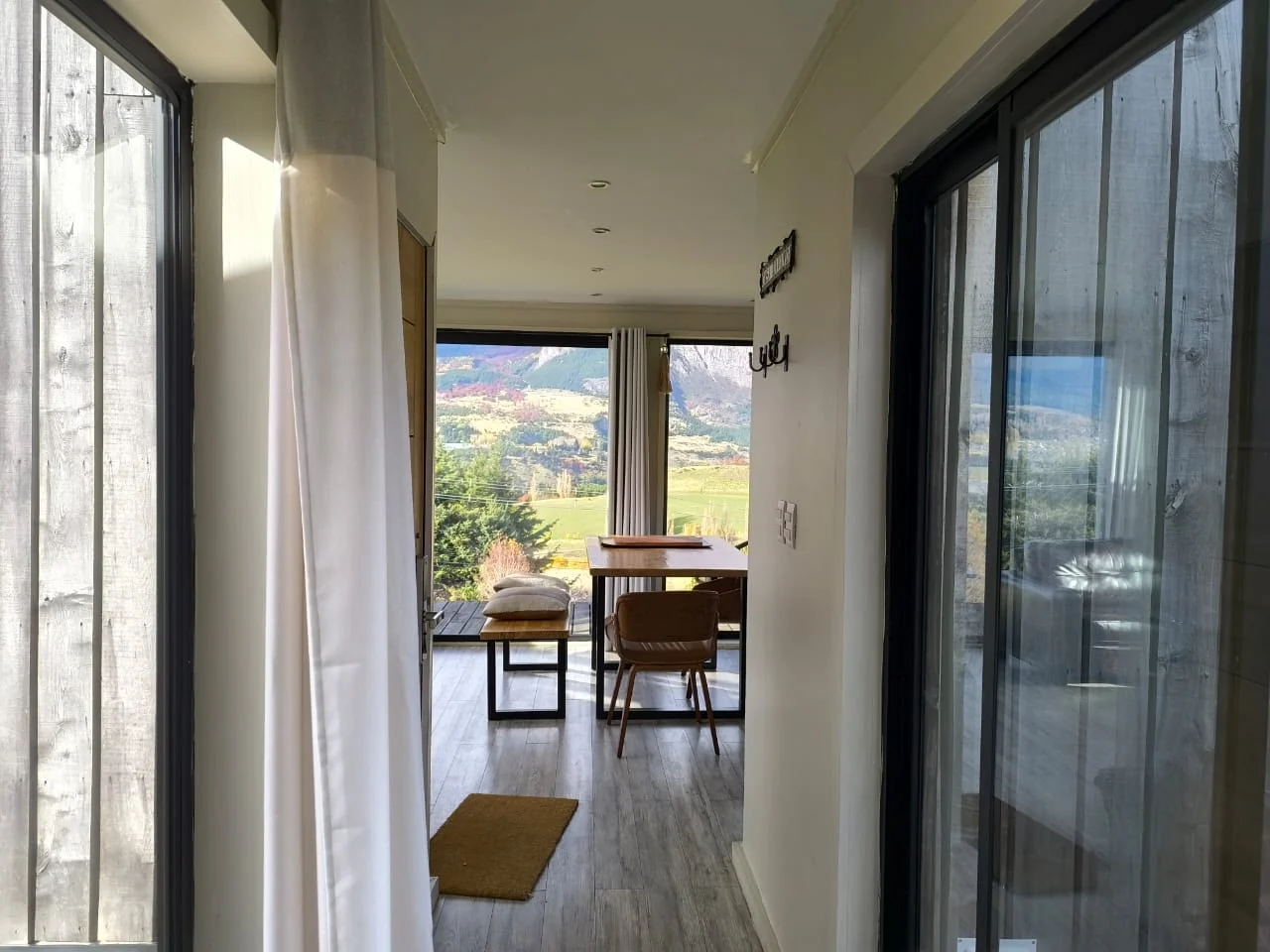 Pasillo luminoso que lleva al comedor y a los ventanales con vista a los cerros